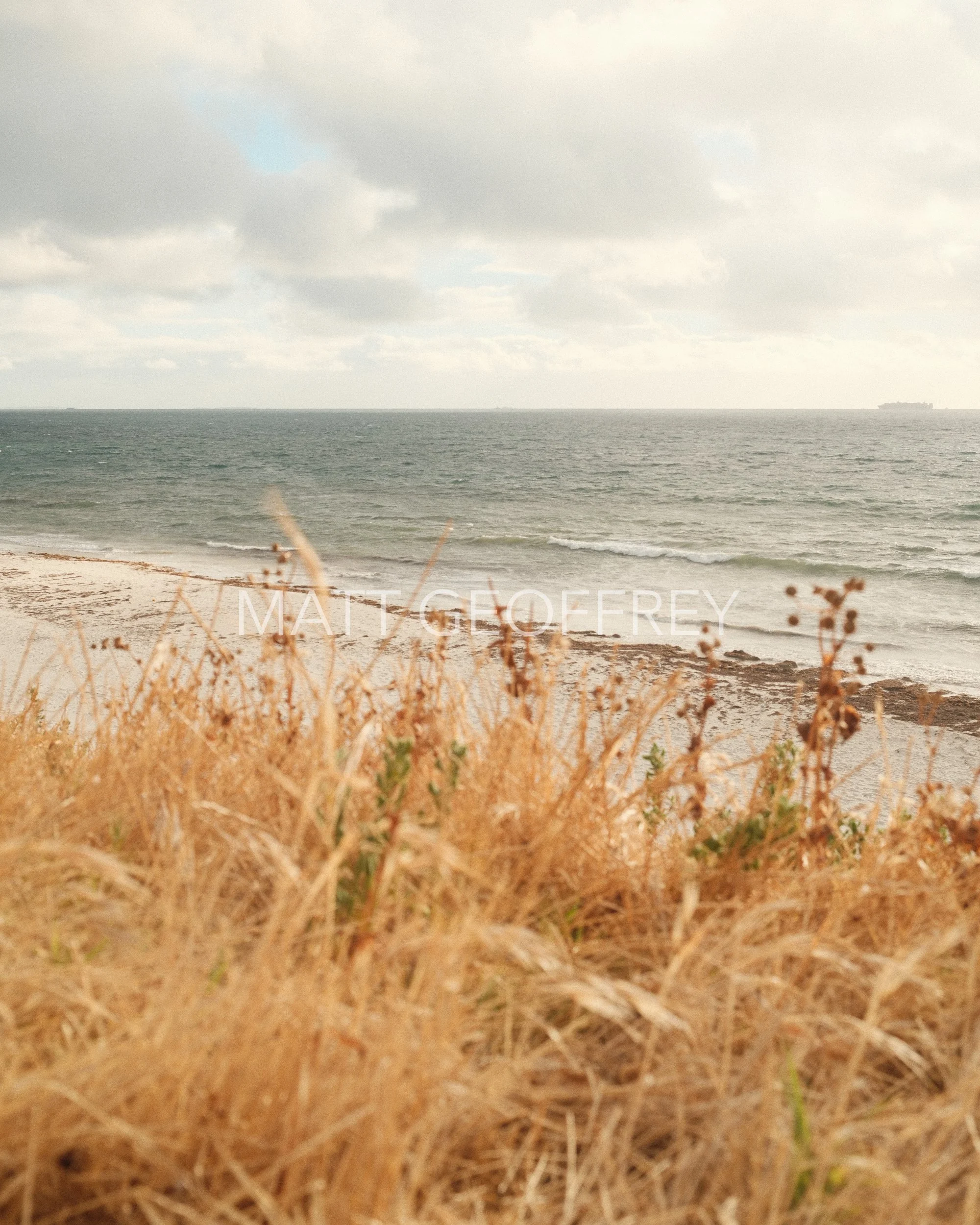 A view of a field looking out towards the ocean on an overcast day