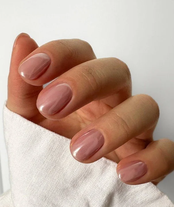 Close-up van een hand met mooi verzorgde, lichtroze nagels.