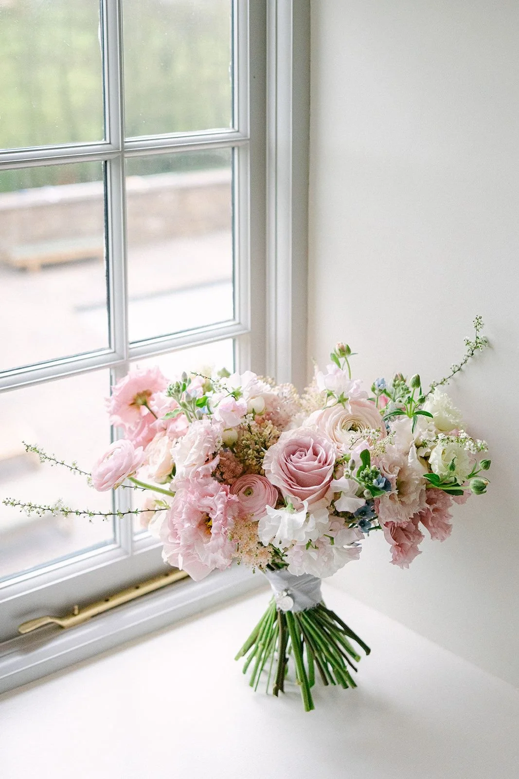 A bouquet of pink and white flowers on a windowsill.