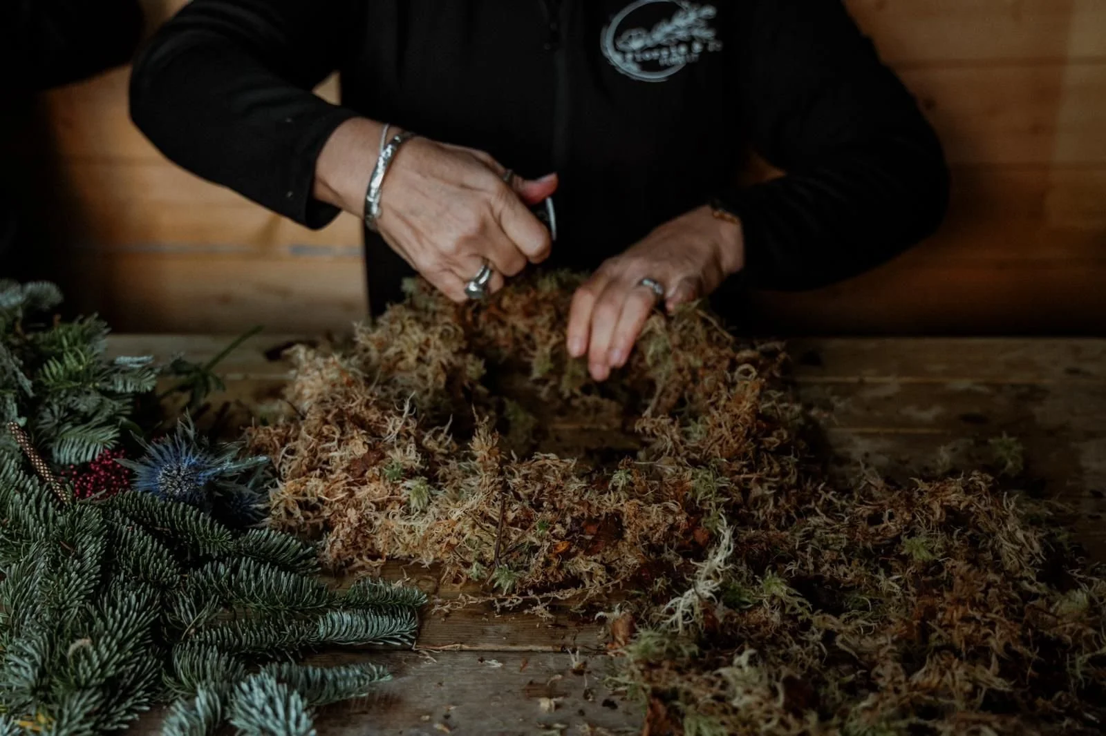 Person preparing cannabis buds with Christmas decorations on the side.