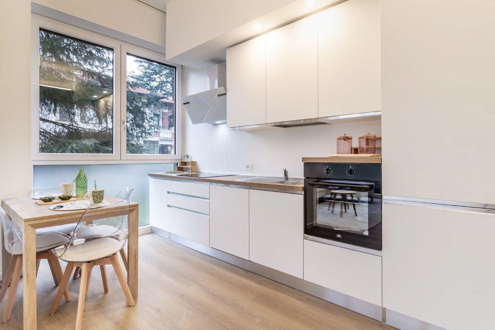 A yellow bean bag chair on a balcony with a small round black table holding a round hedge plant and a spider web.