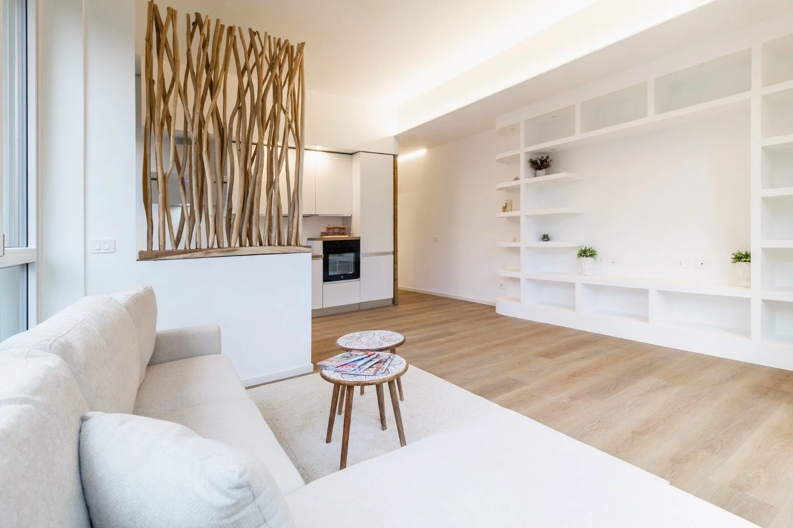 Modern bathroom with a double sink vanity, a mirror, a large window, a toilet, and a glass-enclosed shower with a terrazzo wall.