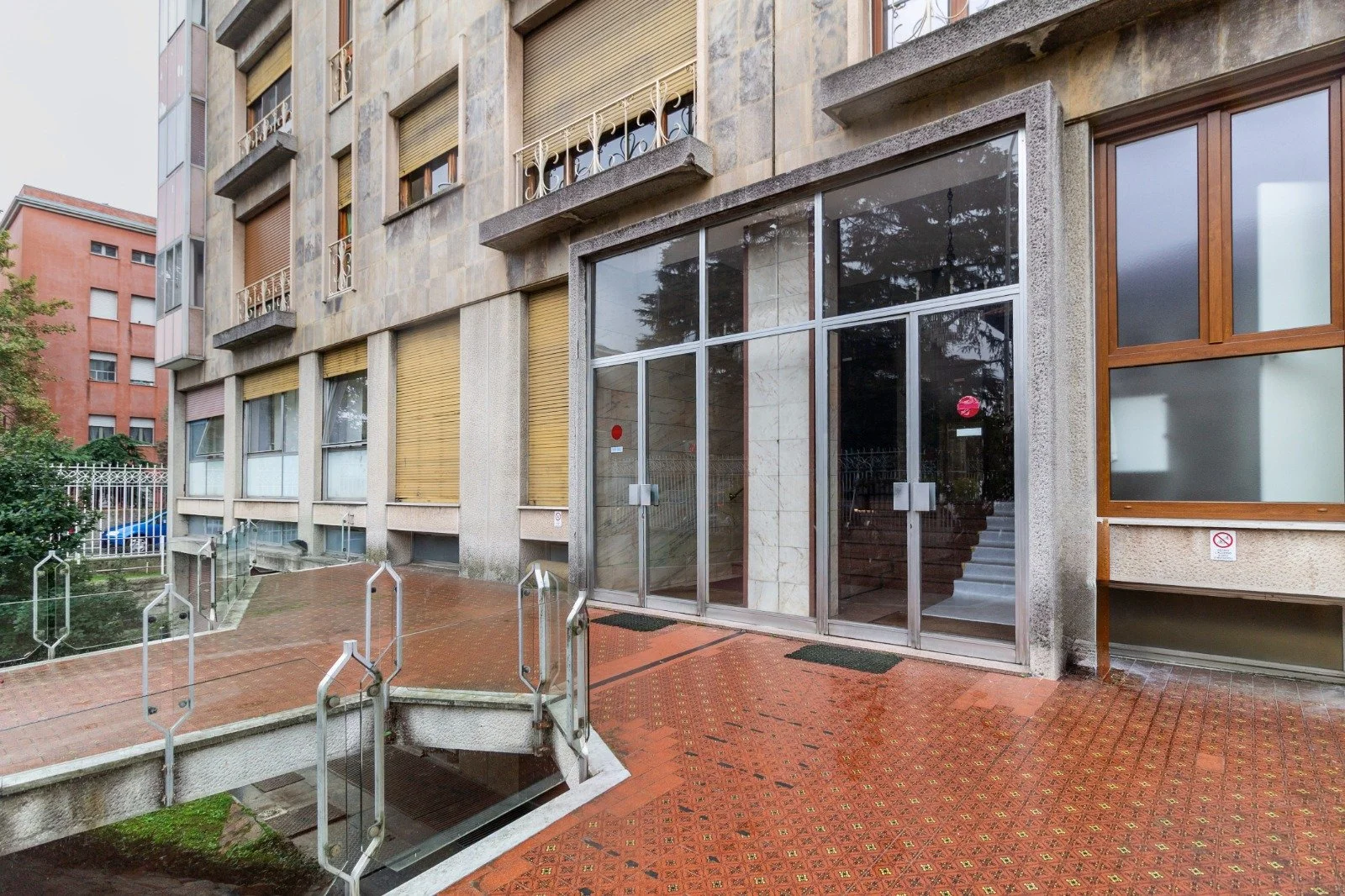 A bed with beige pillows, two green and black striped pillows, and one decorative pillow with a tropical leaf and animal print, against a wall with tropical-themed wallpaper and a partial view of a light switch.