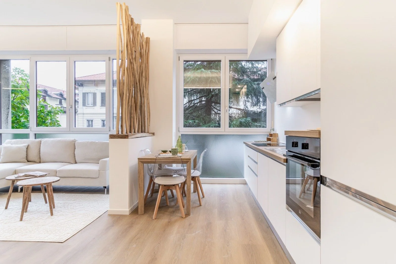 A yellow outdoor lounge chair with matching cushion, a white birdcage with green trailing plant, and a floral-patterned cushion on a balcony with metal railing.