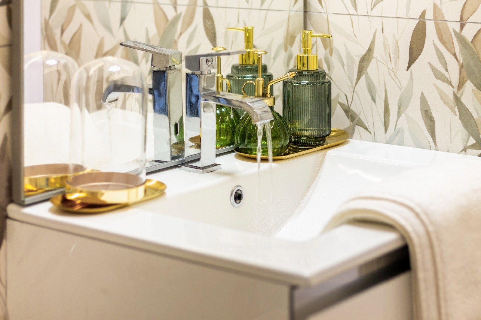 Sunlit corner of a room featuring a table with decorative plants, a posey of pillows with colorful patterns, a modern wooden table lamp, and a window with a view of trees outside.