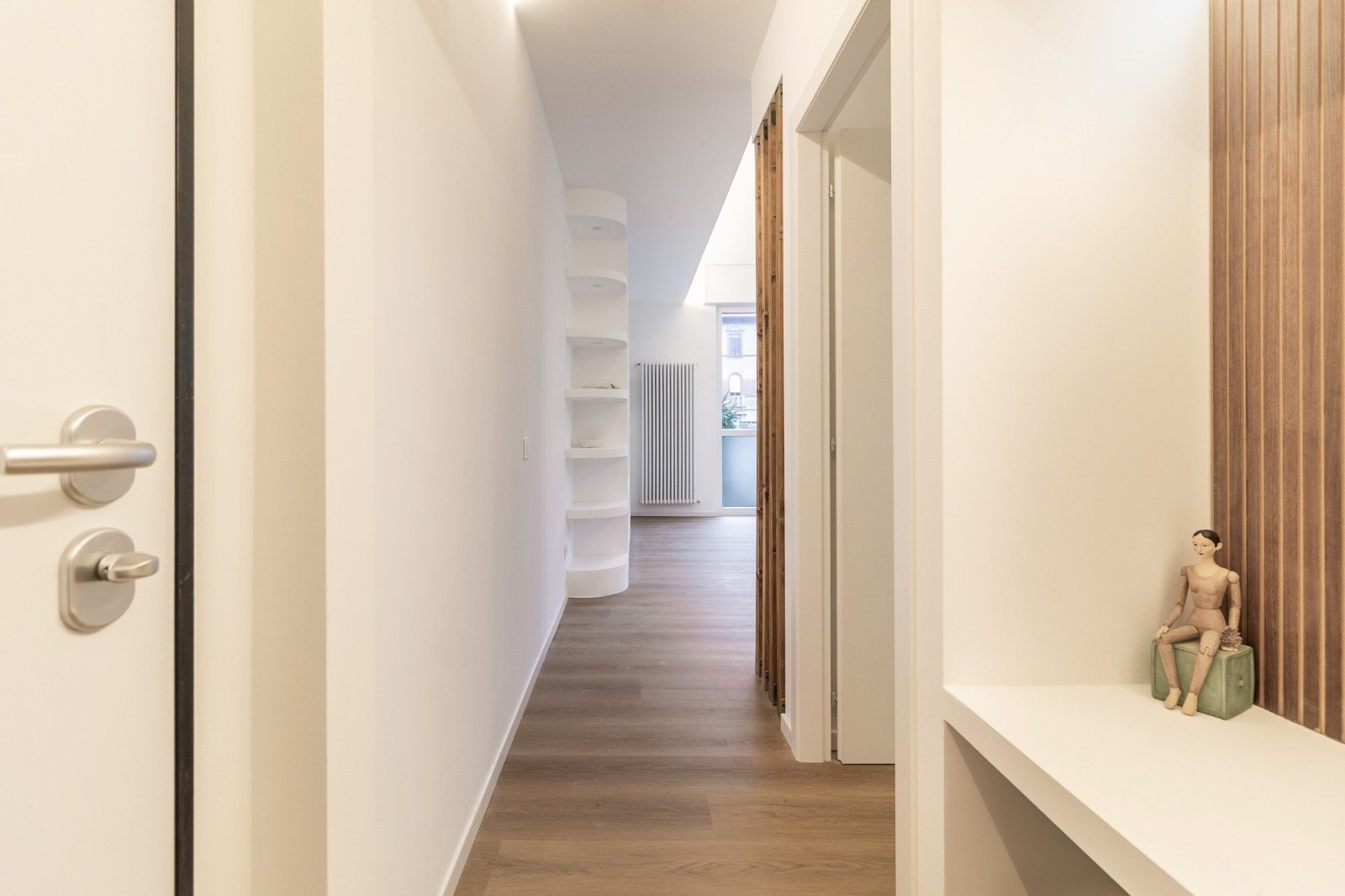 Modern kitchen with white cabinets, wood countertops, built-in oven and microwave, wooden dining table with white chairs, and hardwood flooring.