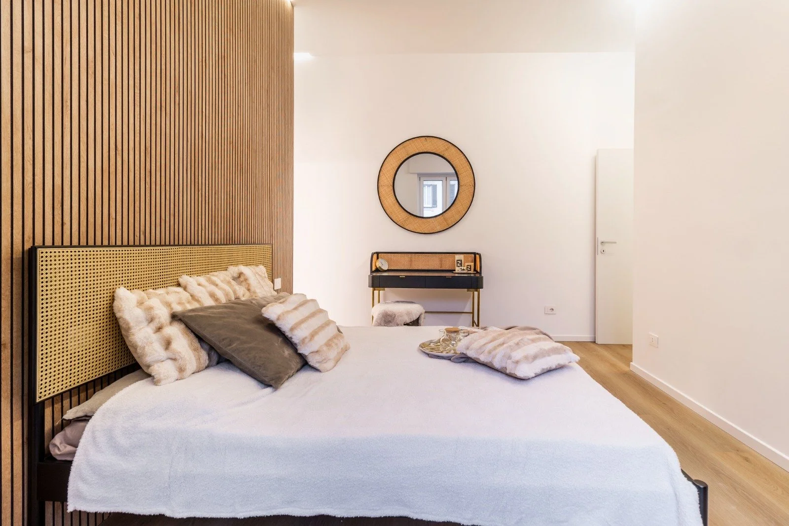 Close-up of a bed with two floral pattern pillows featuring birds, against a plain wall.