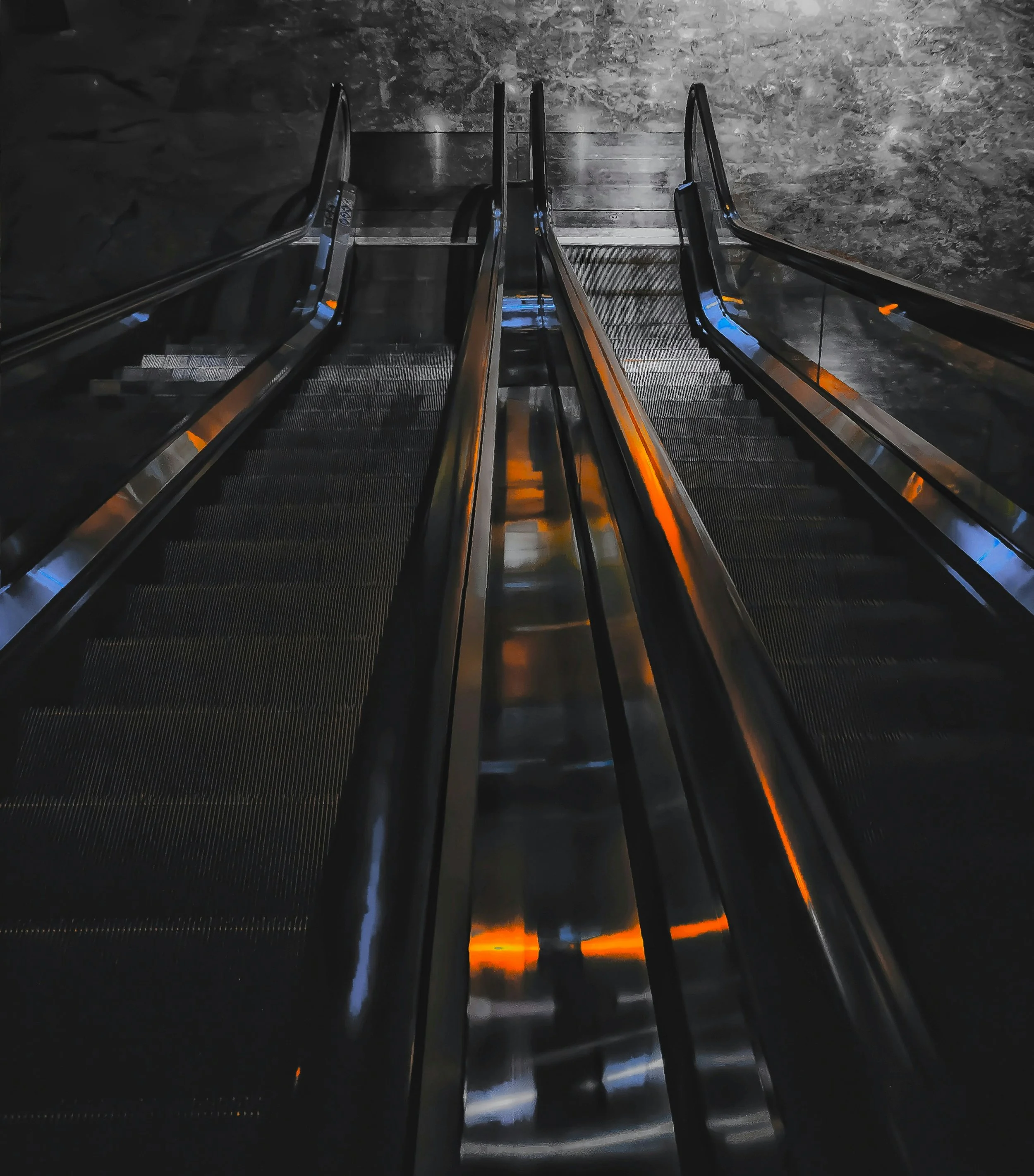 Escadas rolantes de metal com iluminação laranja, vista de cima, em ambiente interno com paredes de pedra.