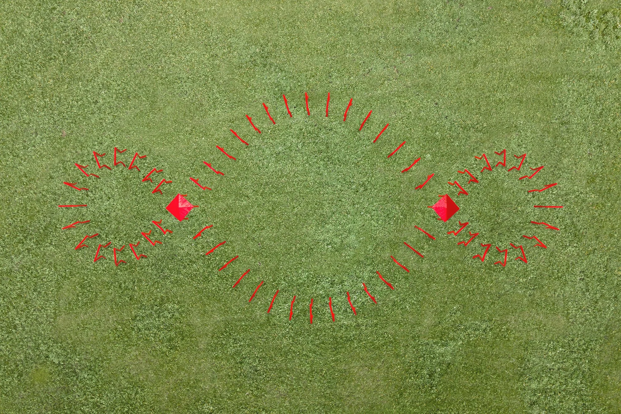 An aerial view shows a red art installation on a green field