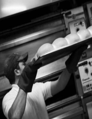A Friary Mill baker loading baked bread into a cooling rack.