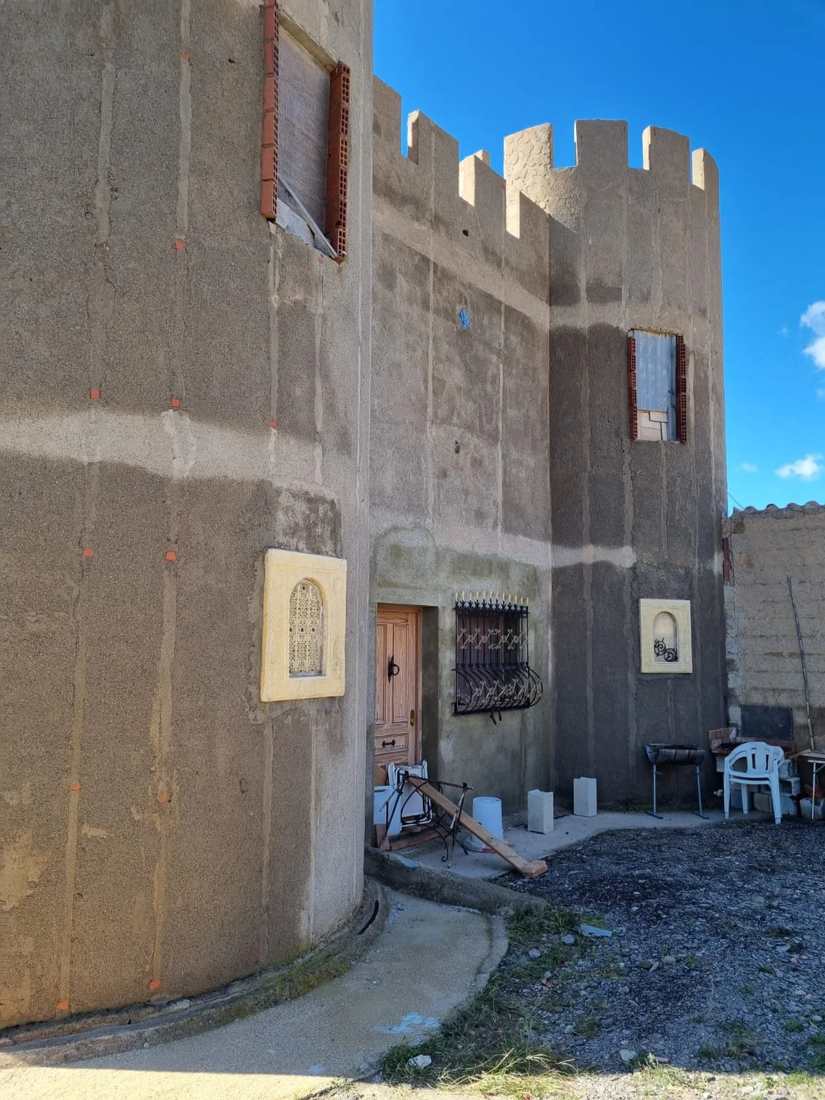 Un fertig gebautes steinernes Schloss mit Zinnen, Fenster und Tür, im Freien bei sonnigem Himmel.