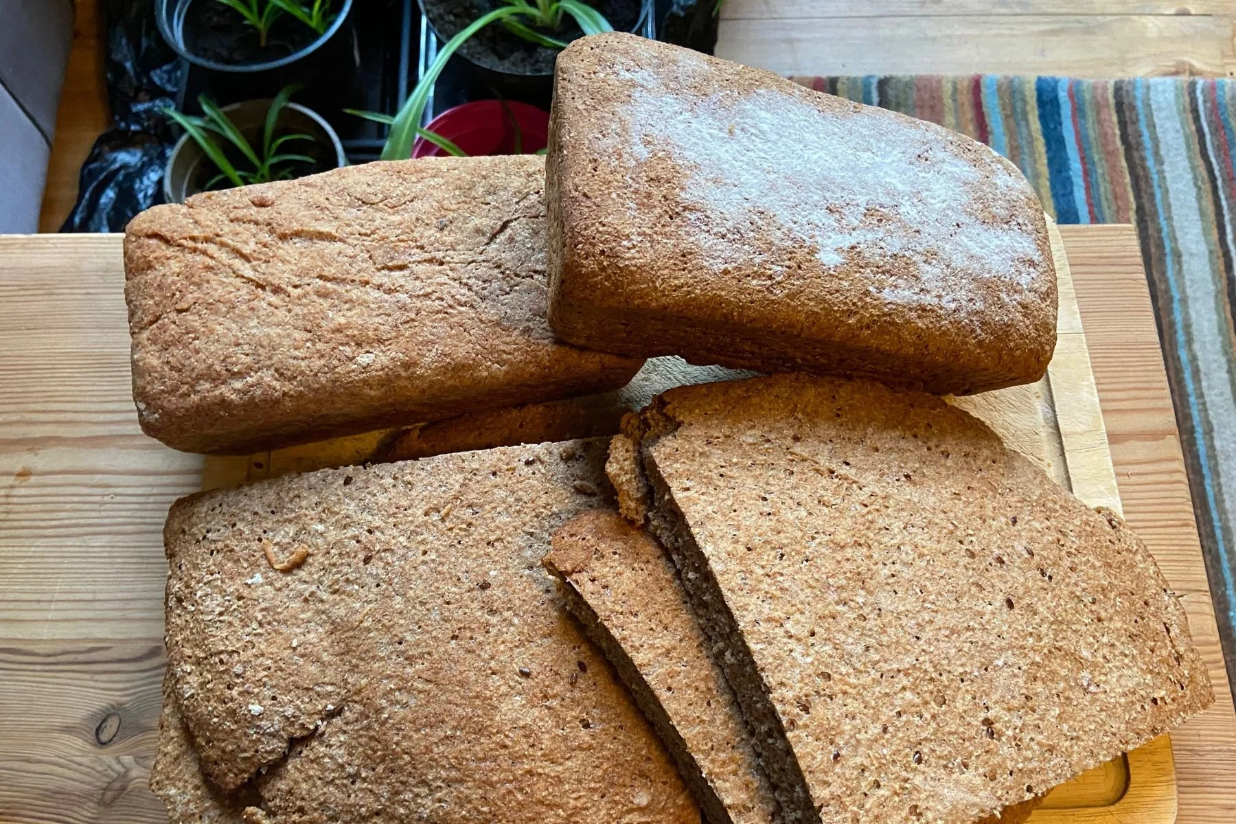 Four rustic leaves are cut and arranged on a wooden cutting board. This bread is made from wheat grown as part of the St James's Daily Bread project.