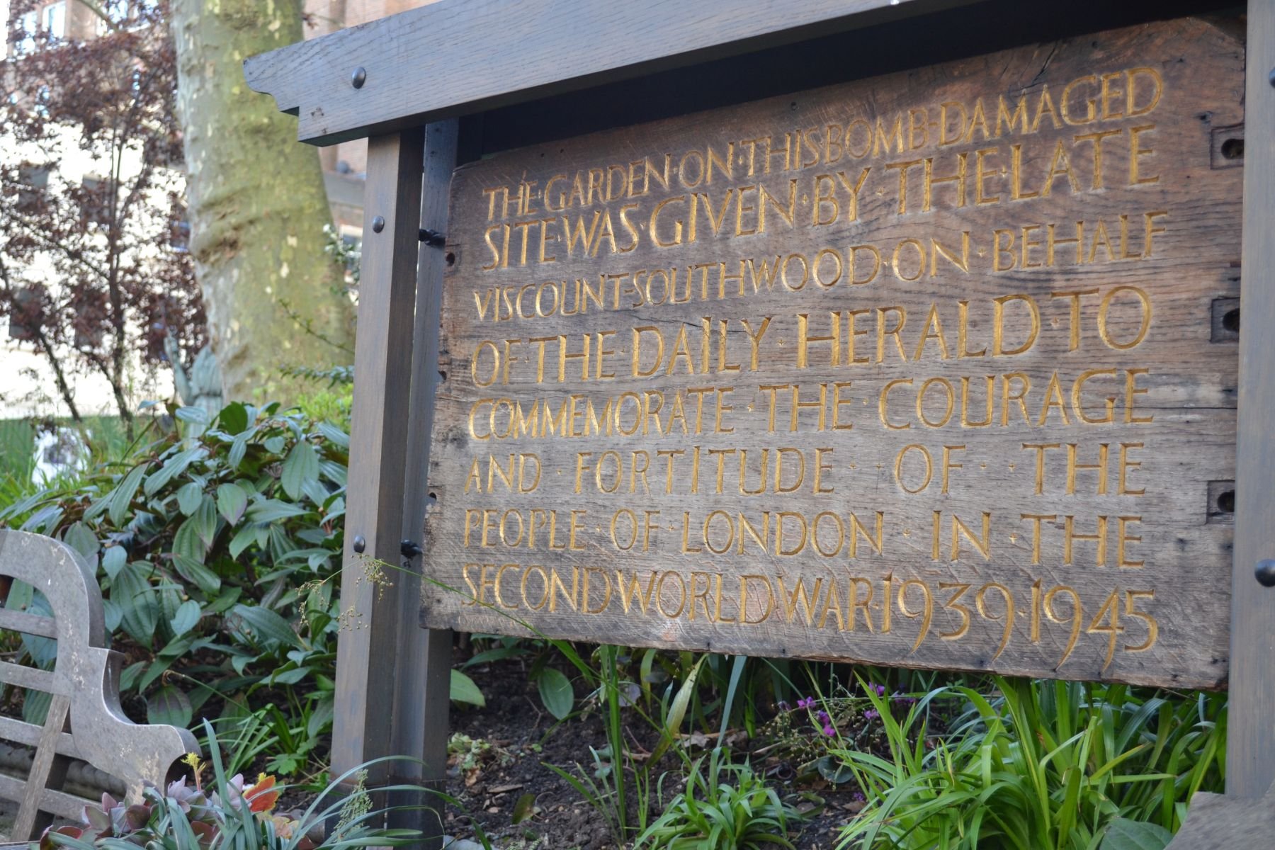 Wooden memorial sign in the Southwood Garden at St James's Piccadilly about the bombing damage at the church during the Second World War, honouring the courage and fortitude of the people of London.