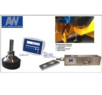 A digital control device connected to a mechanical component, with a thumb wheel switch, a black base, and a metal measuring tool on a white surface, with part of a blue and yellow industrial machine in the background.