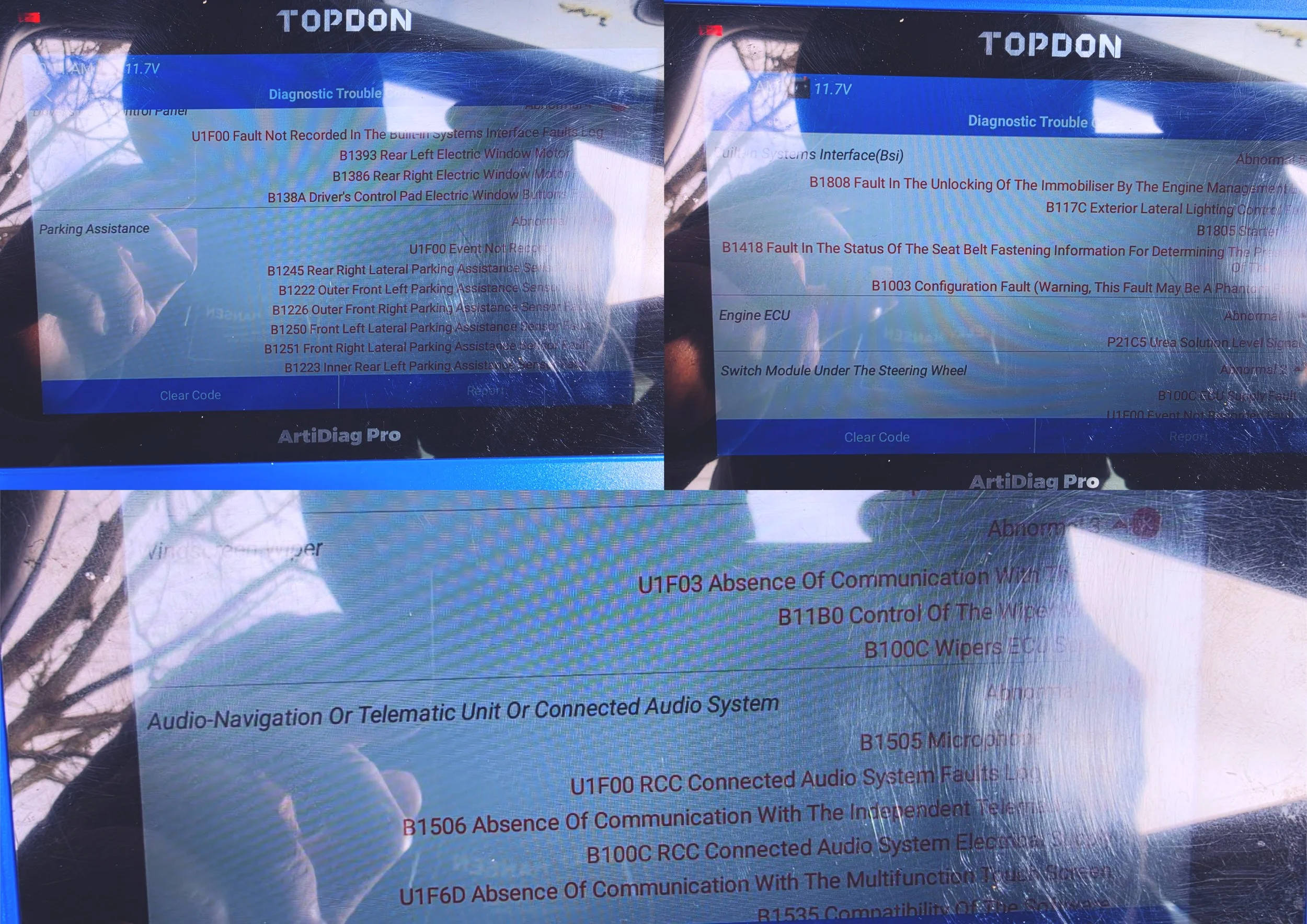 A vehicle diagnostic scan tool screen displaying various error codes and system information, with reflections of the surroundings captured on the screen.