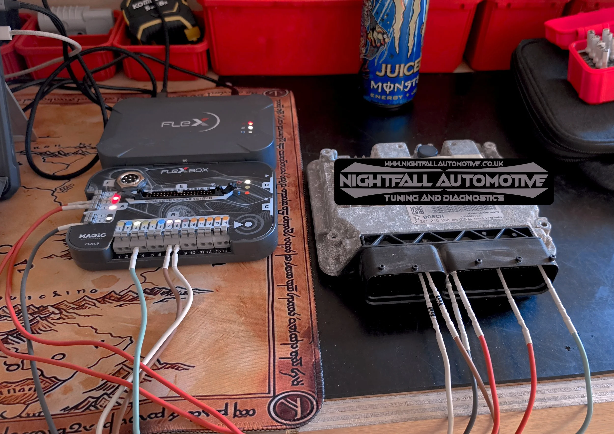 The image shows a workbench with automotive tuning and diagnostic tools. There is a Flex connector, a control box, an ECU (engine control unit), a wiring harness, and a small box with electrical connectors. In the background, there are red tool organ