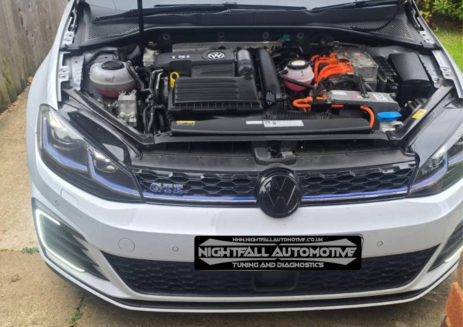 Front view of a white Volkswagen car with the hood open, revealing the engine bay.