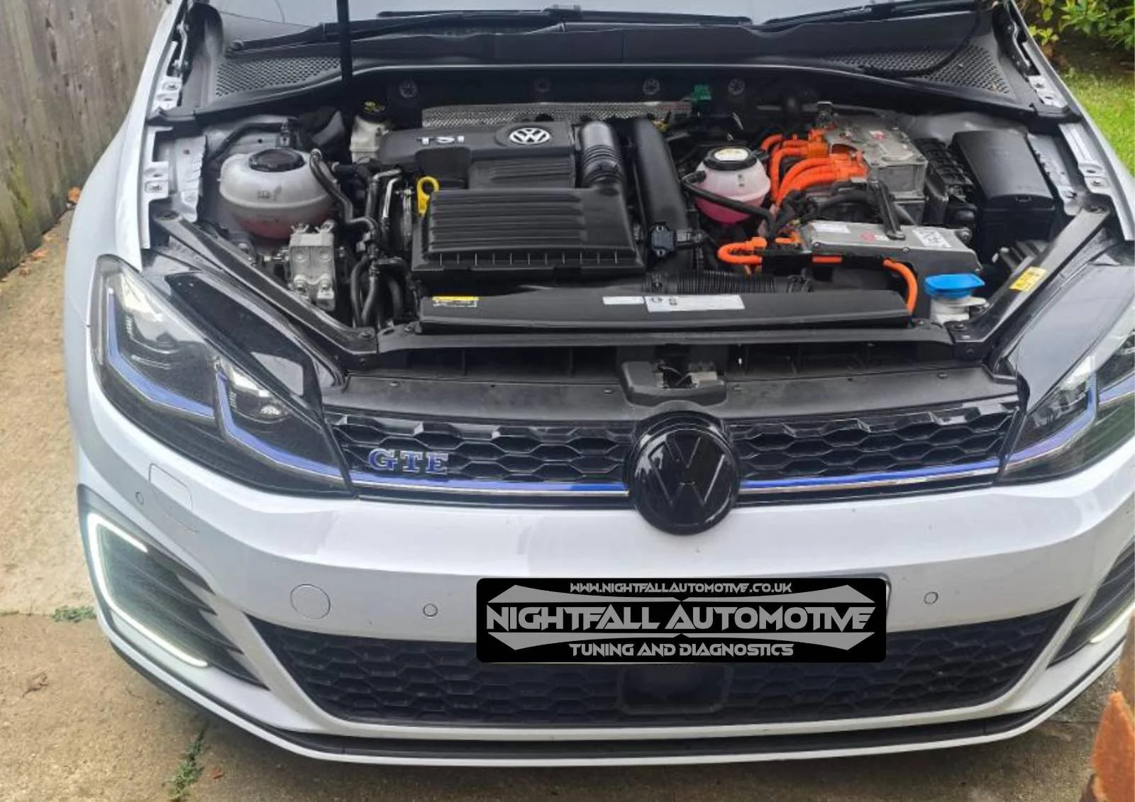 Front view of a white Volkswagen car with the hood open, revealing the engine bay.