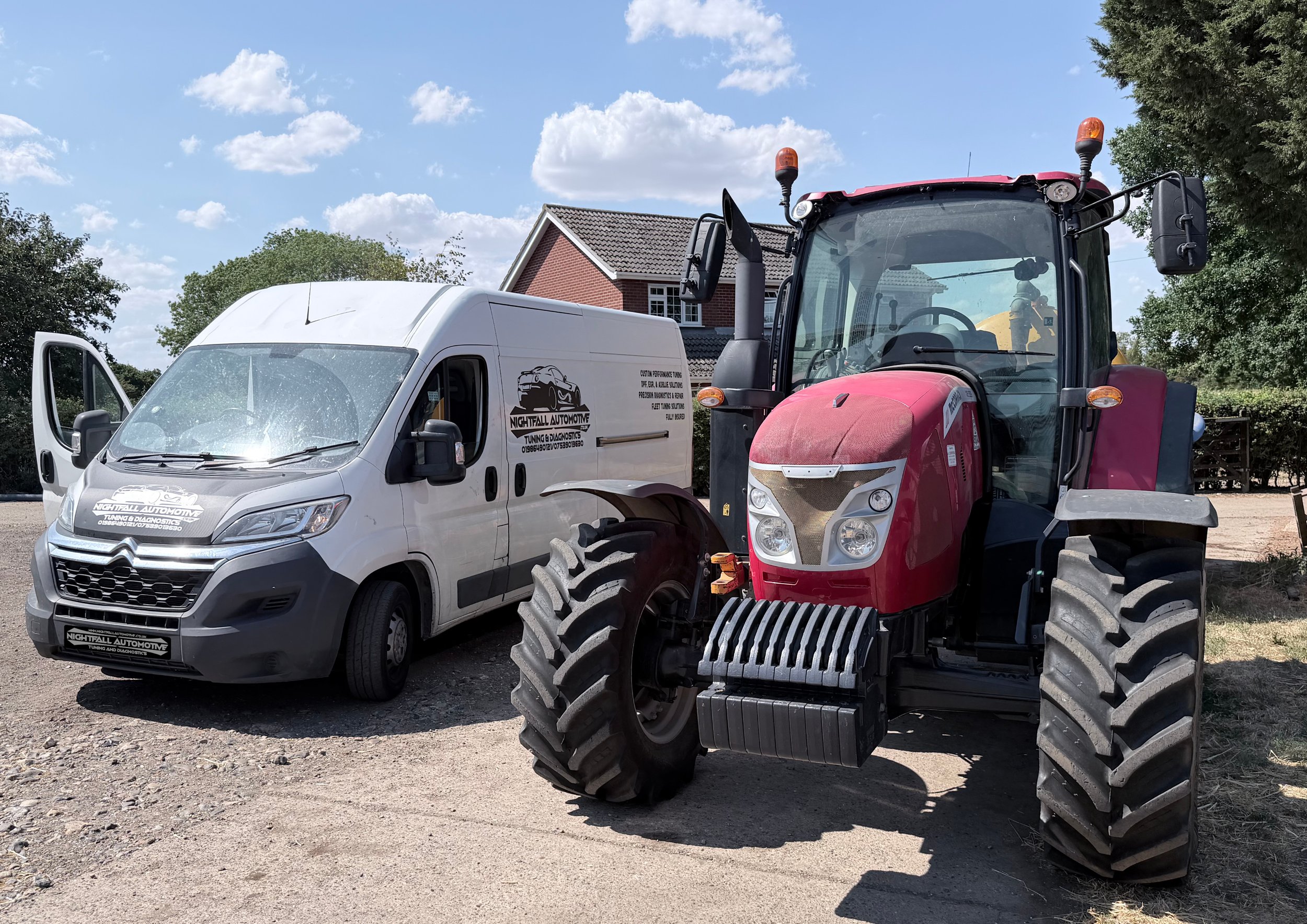 A white van and a red tractor parked side by side on a gravel surface, with a house and trees in the background under a partly cloudy sky.
Tuned by Nightfall Automotive
