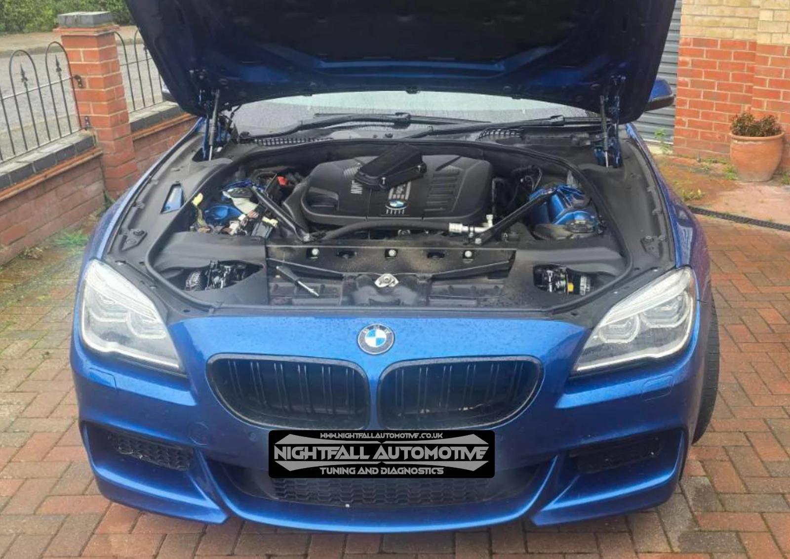 Blue BMW with the hood open, showing the engine bay with branding of Nightfall Automotive on the front license plate.