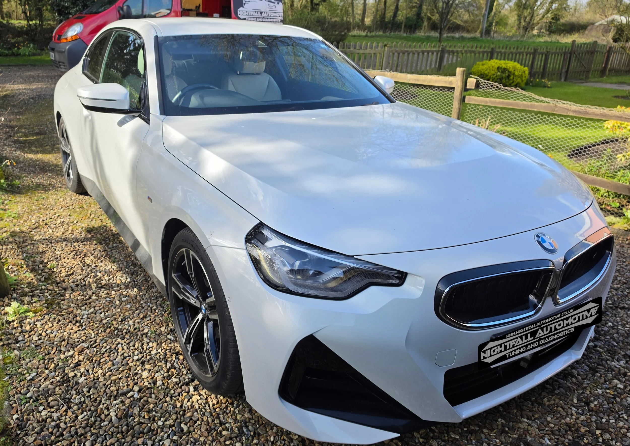 A white BMW parked outdoors on a gravel surface with Nightfall Automotive checking if the ECU is locked