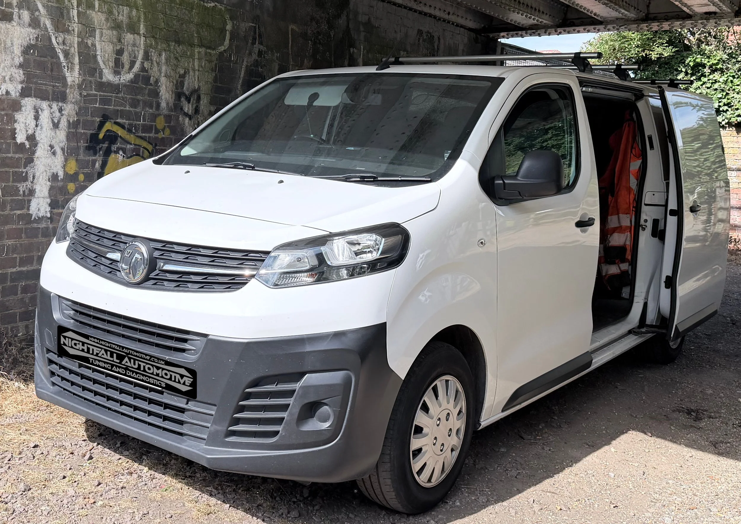 A white commercial van parked under a bridge, Tuned by Nightfall Automotive