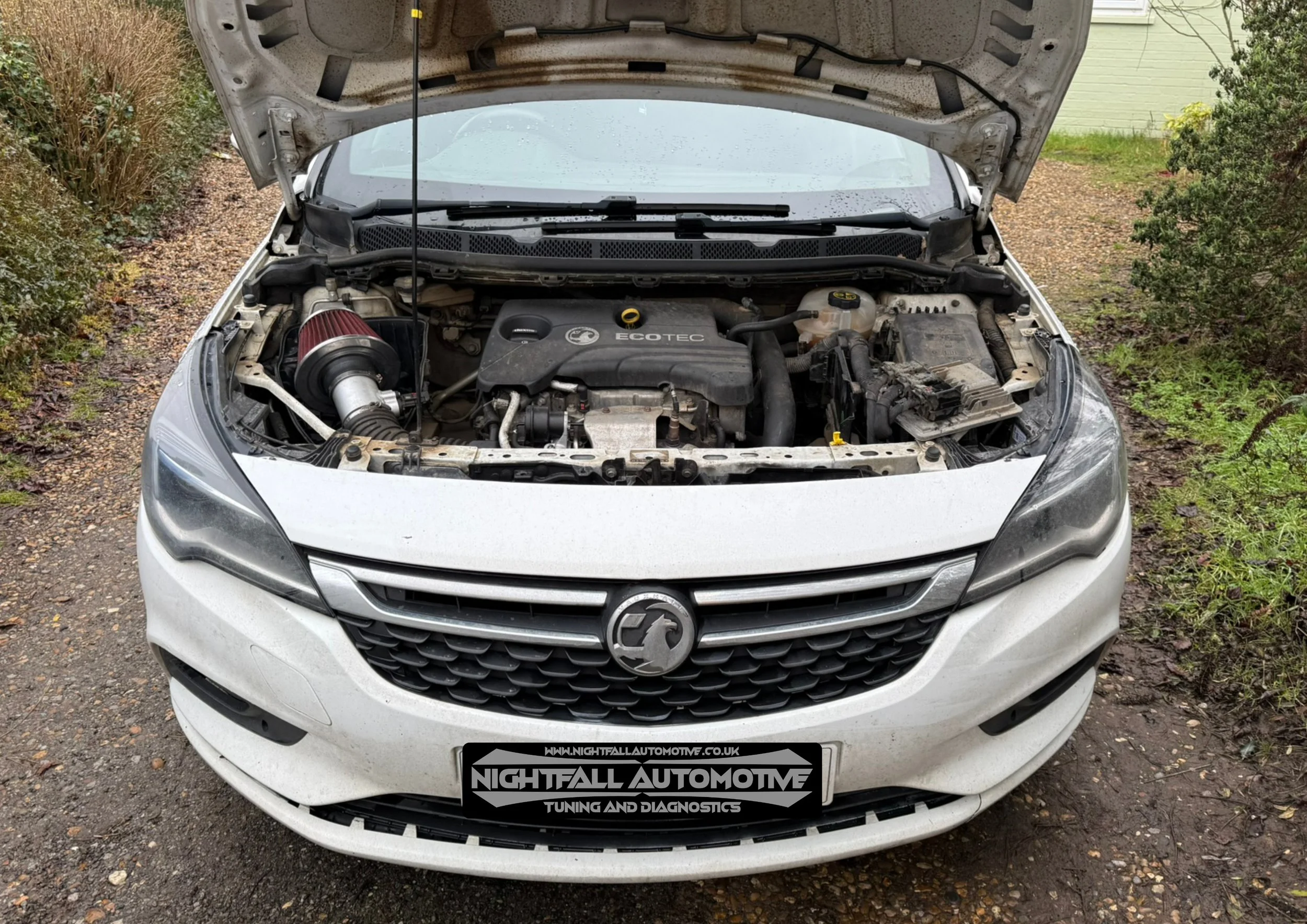 Front view of a white Holden car with its hood open, showing the engine bay with a red air filter on the left side, and a license plate reading Nightfall Automotive.