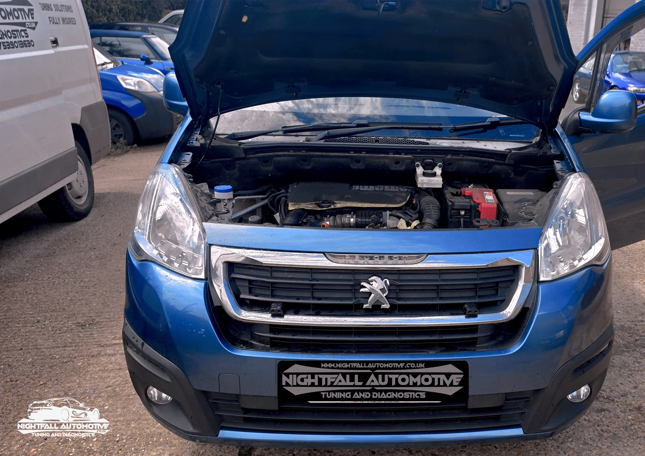 Front view of a blue Peugeot car with its hood open, parked among other vehicles. The photograph is taken at a car dealership or garage, with the logo of Nightfall Automotive visible on a sign at the bottom. tuned by Nightfall Automotive