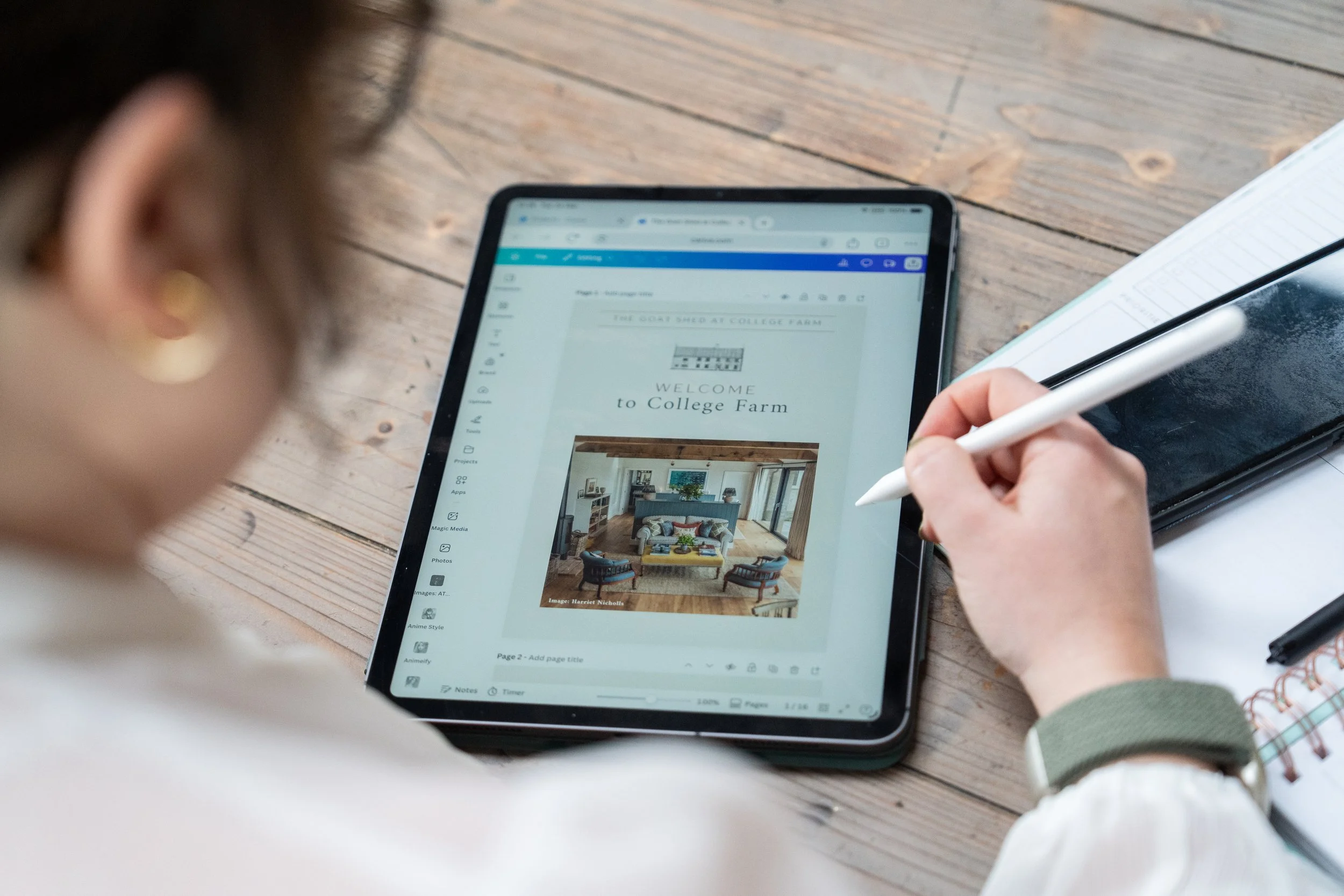 Virtual Assistant using a stylus to work on a digital tablet displaying a Canva webpage design for a wedding venue