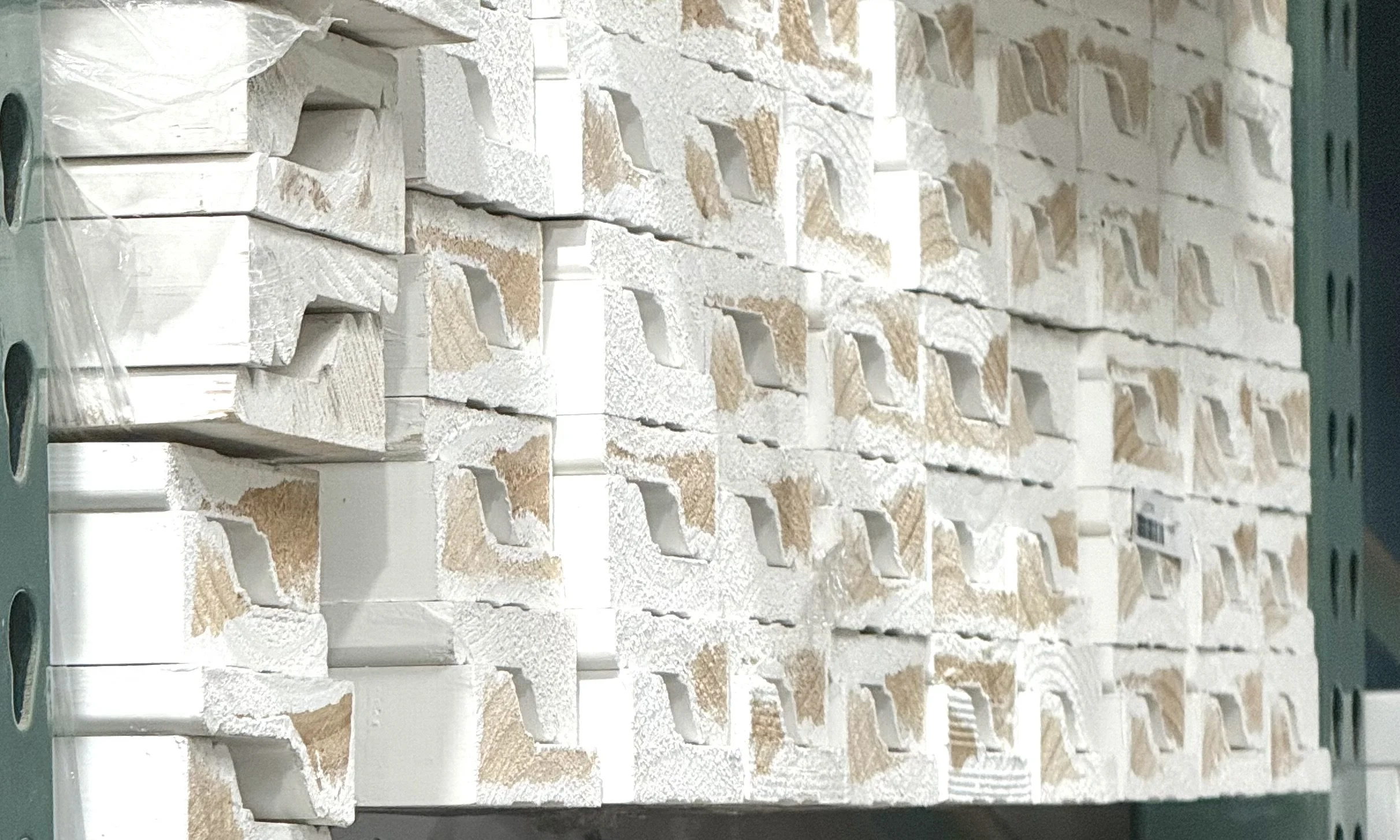 Stacked door casing insulation panels on a metal shelf in a storage or construction area.