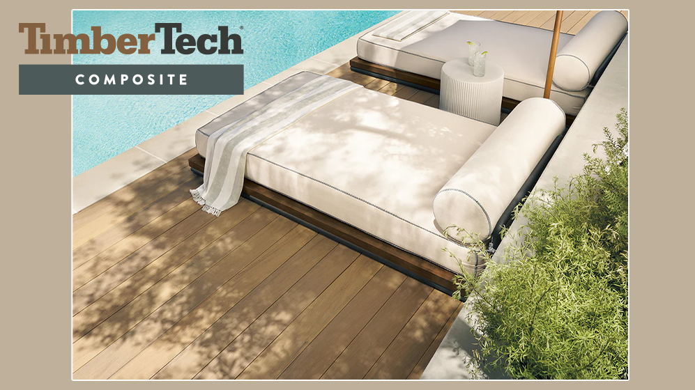 Outdoor wooden deck with cream-colored douglas timberTech composite furniture and a pool in the background. There is a small white side table with a glass of water, and a striped throw blanket on the furniture. Green plants are on the side.
