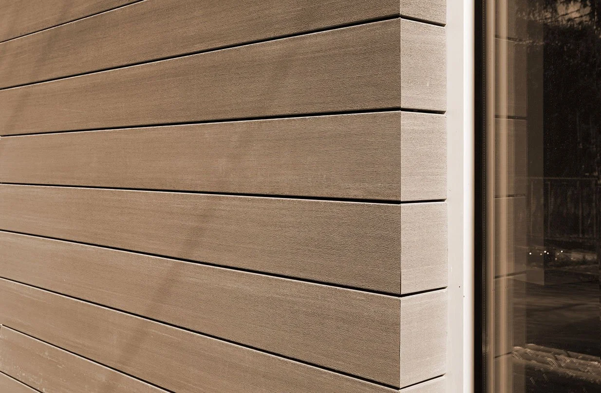 Close-up of beige horizontal wooden siding and a corner of a sliding glass door.