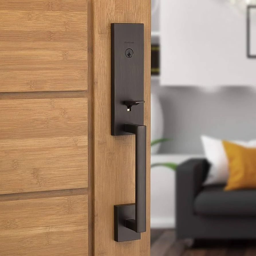 Modern black electronic door lock with a handle, mounted on a wooden door frame inside a living room.