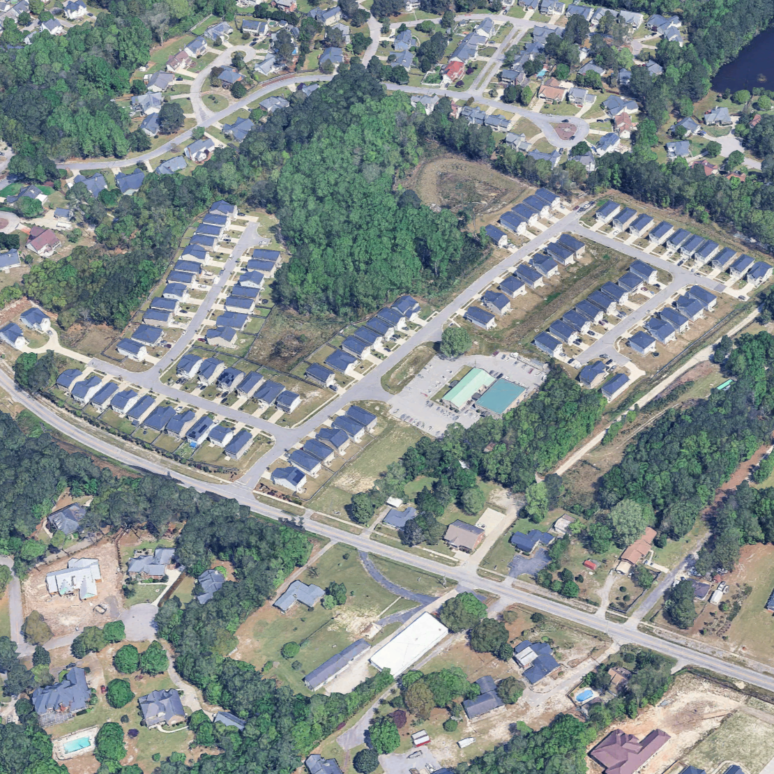 Aerial view of a suburban neighborhood with houses, roads, and a community pool.