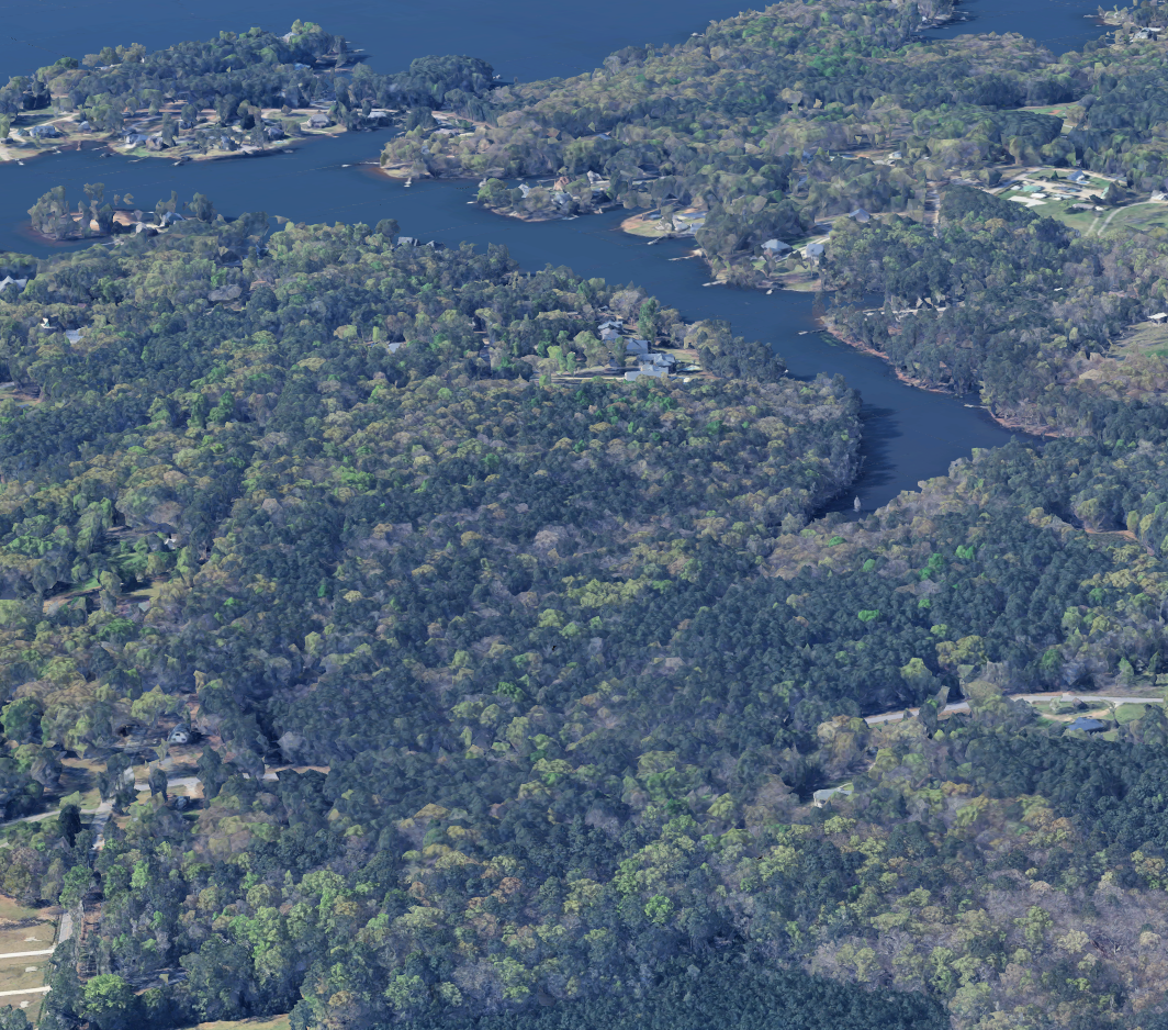 Aerial view of a winding lake surrounded by dense forest and residential neighborhoods.