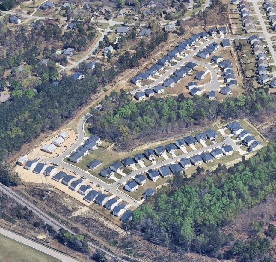 Aerial view of a residential neighborhood with houses, green trees, and winding roads.