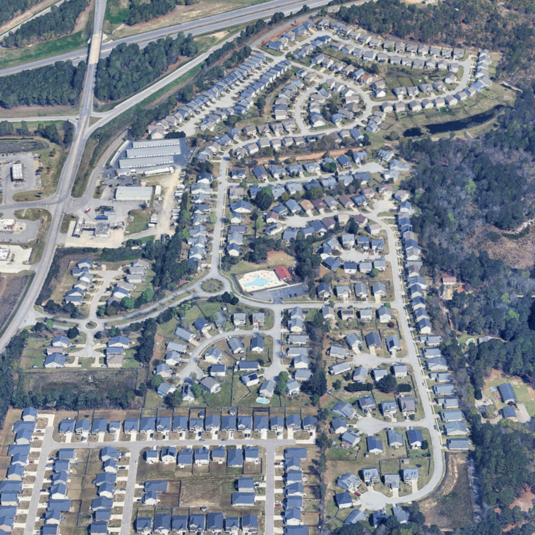 Aerial view of a suburban neighborhood with winding streets, houses, a swimming pool, and surrounding greenery.
