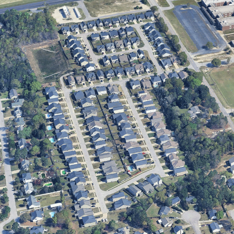Aerial view of a residential neighborhood with rows of houses, trees, and some open green spaces.