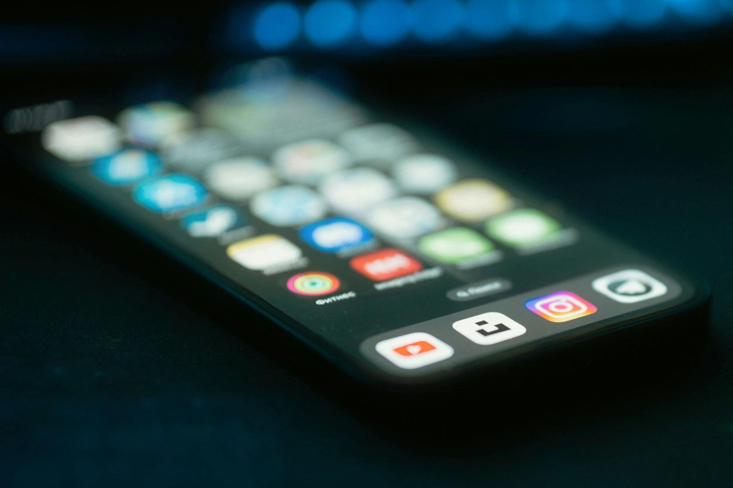 Close-up of a smartphone screen displaying app icons on a black surface.
