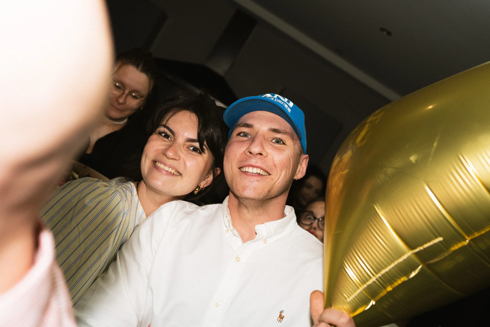 Groupe de personnes souriantes lors d'une célébration avec un ballon doré pendant un annivesaire.
