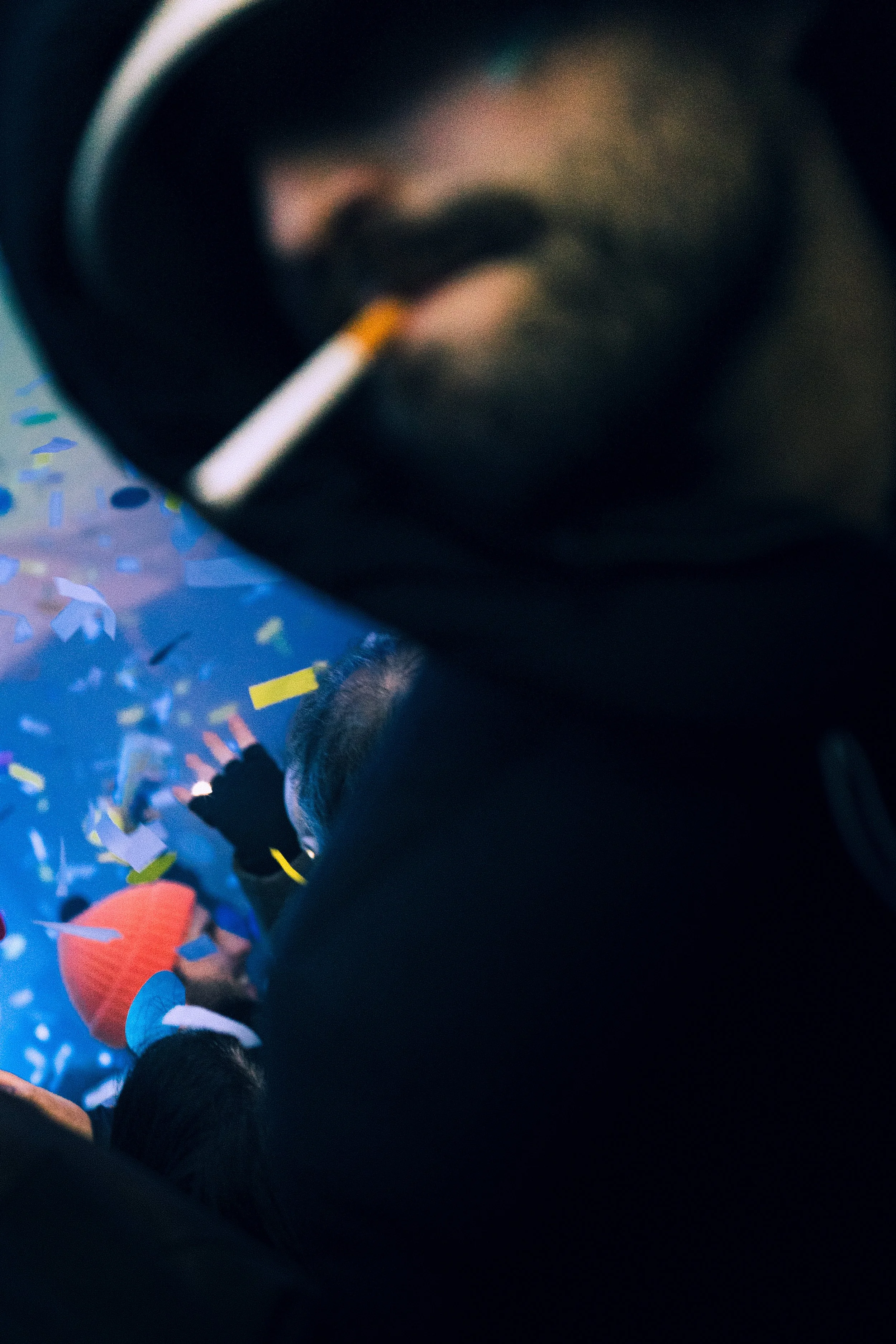 Personnes lors d'une fête, avec des confettis colorés, une personne porte un bonnet orange et d'autres portent des bonnets blancs. Pendant le festival Jacques Fromages.