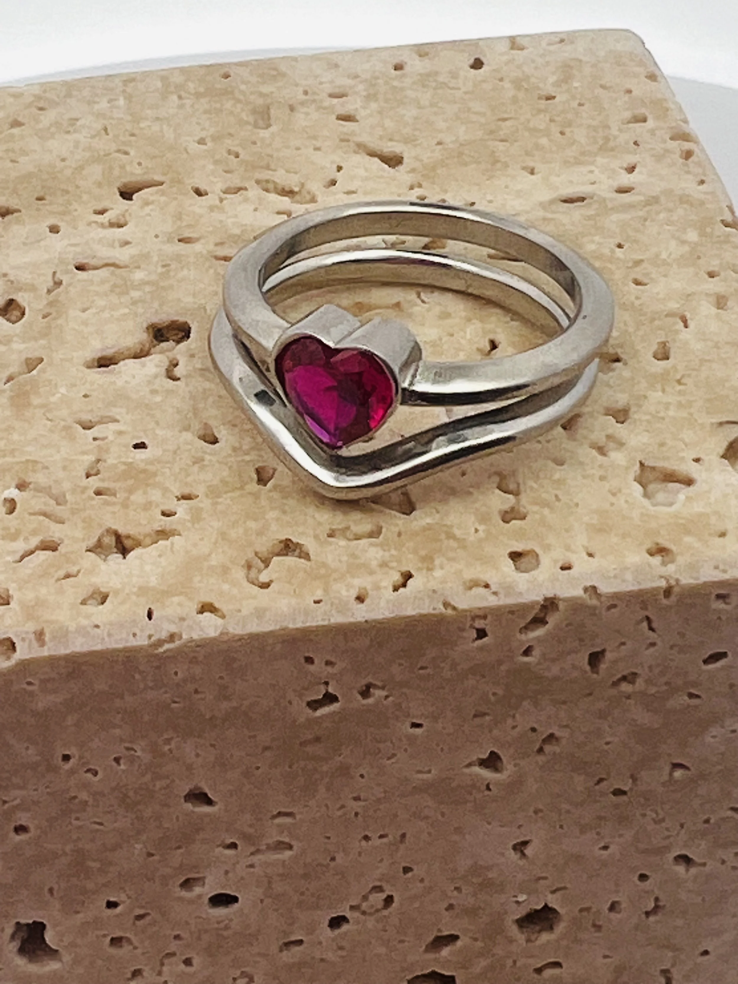 A gold-colored ring with cut-out star and square shapes around it, placed on a white surface.