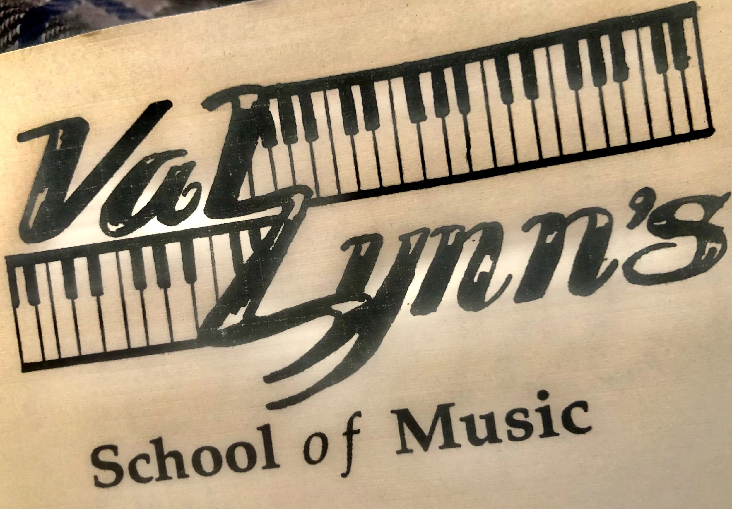 Logo of Vals Legacy School of Music featuring a musical staff with a piano keyboard design in black and white, and text below reading 'School of Music'.