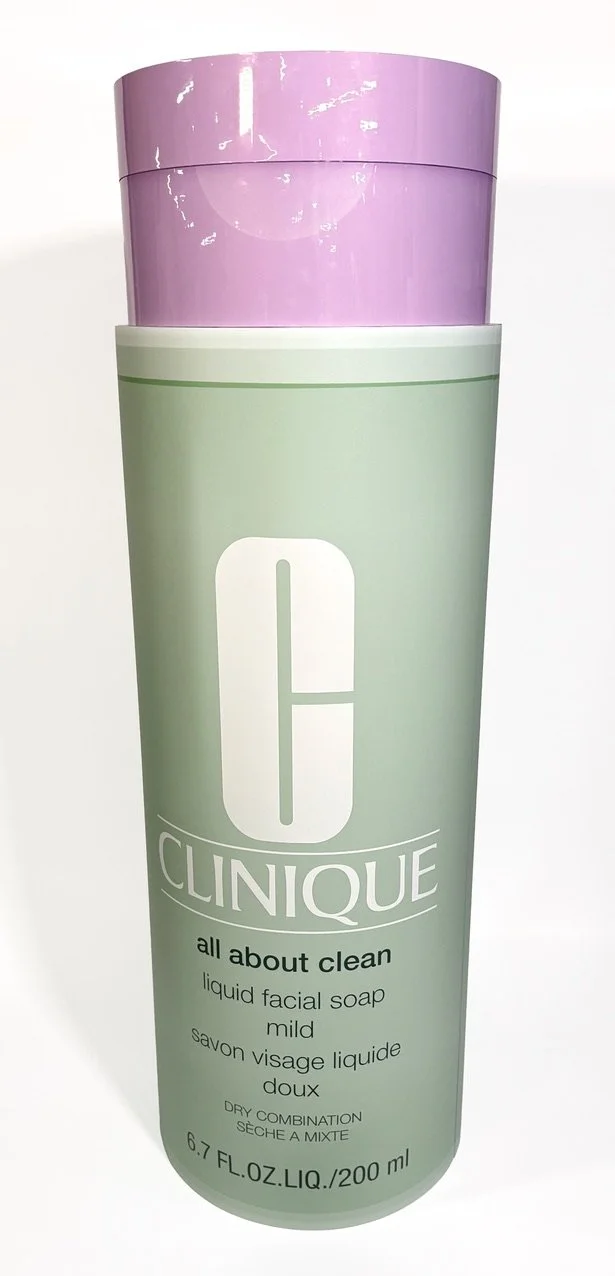 A tall, oversize cylindrical bottle of Clinique liquid facial soap, light green with a purple cap, labeled "all about clean," for dry combination skin, 200 ml.