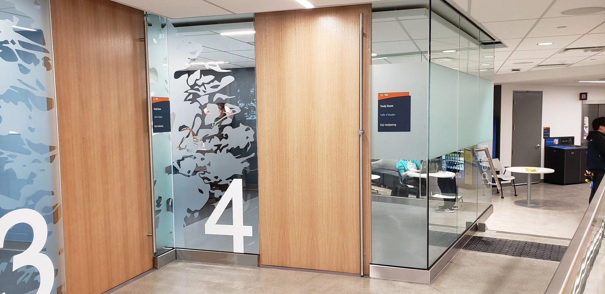 ~Glass door with frosted plant design and the number 4, leading to a study room in a modern library or educational facility.