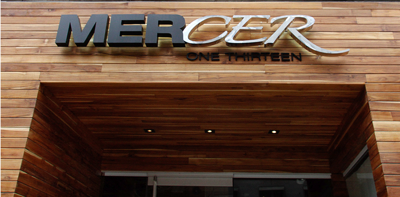 ~Sign reading 'MERCR' and 'ONE THIRTEEN' on a wooden building exterior.