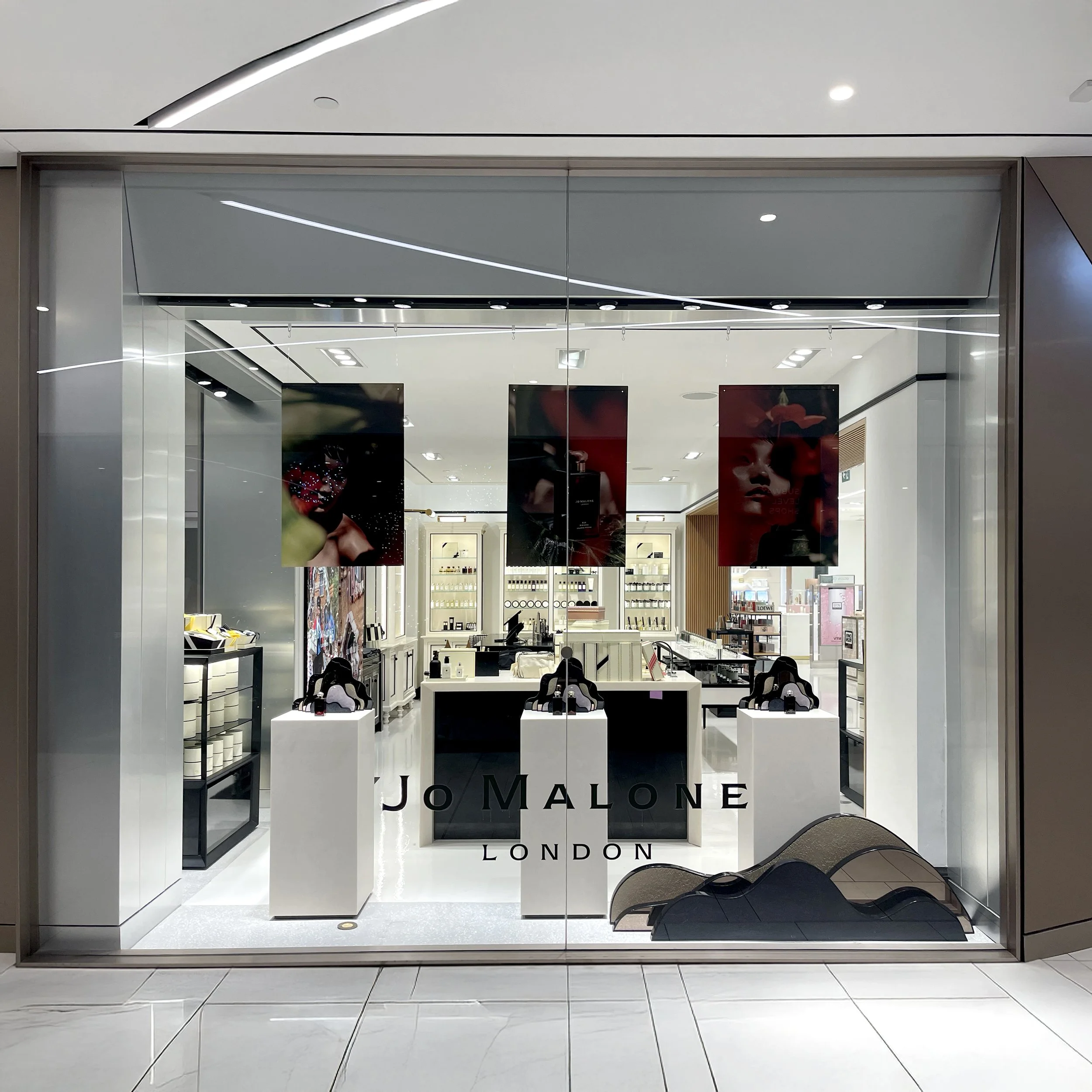 ~Storefront of Jo Malone London in a shopping mall, with display tables and promotional posters inside.