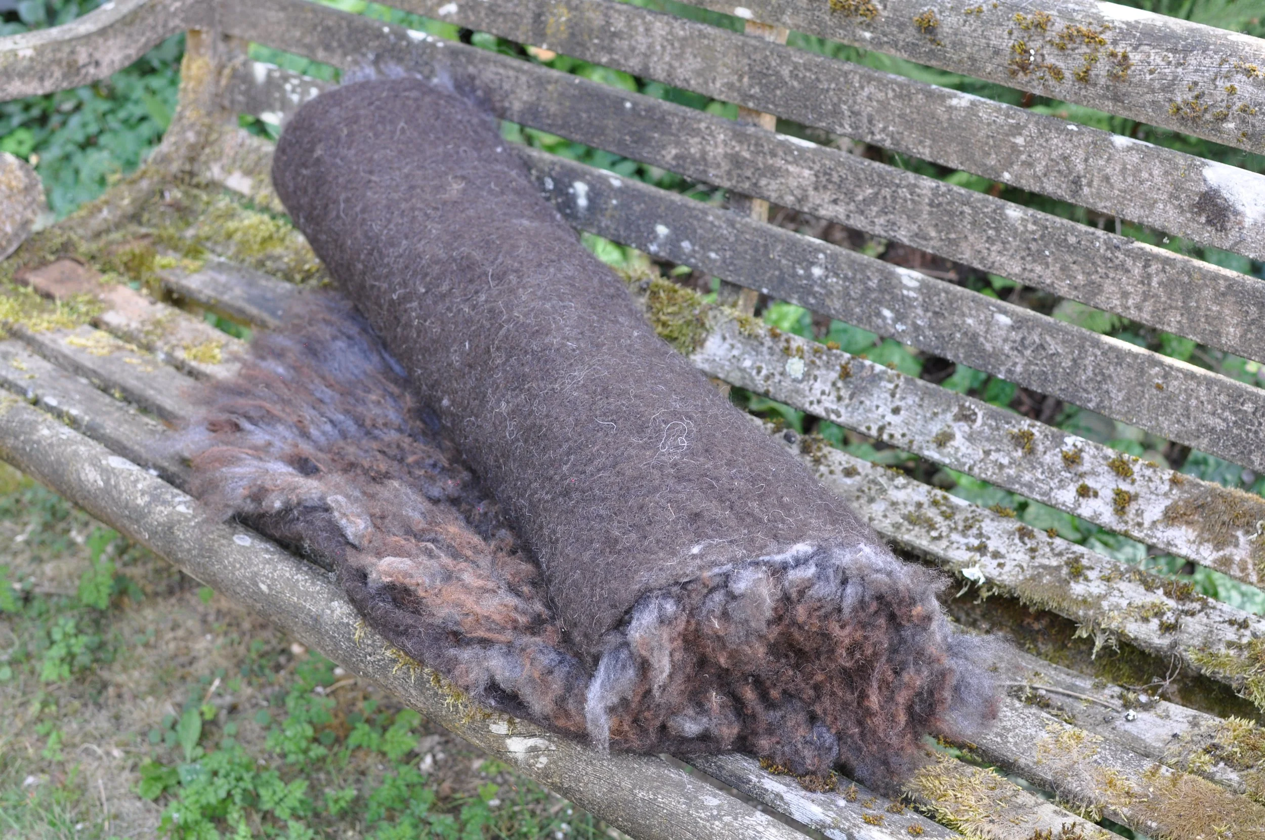 Rolled felted rug on a bench outside