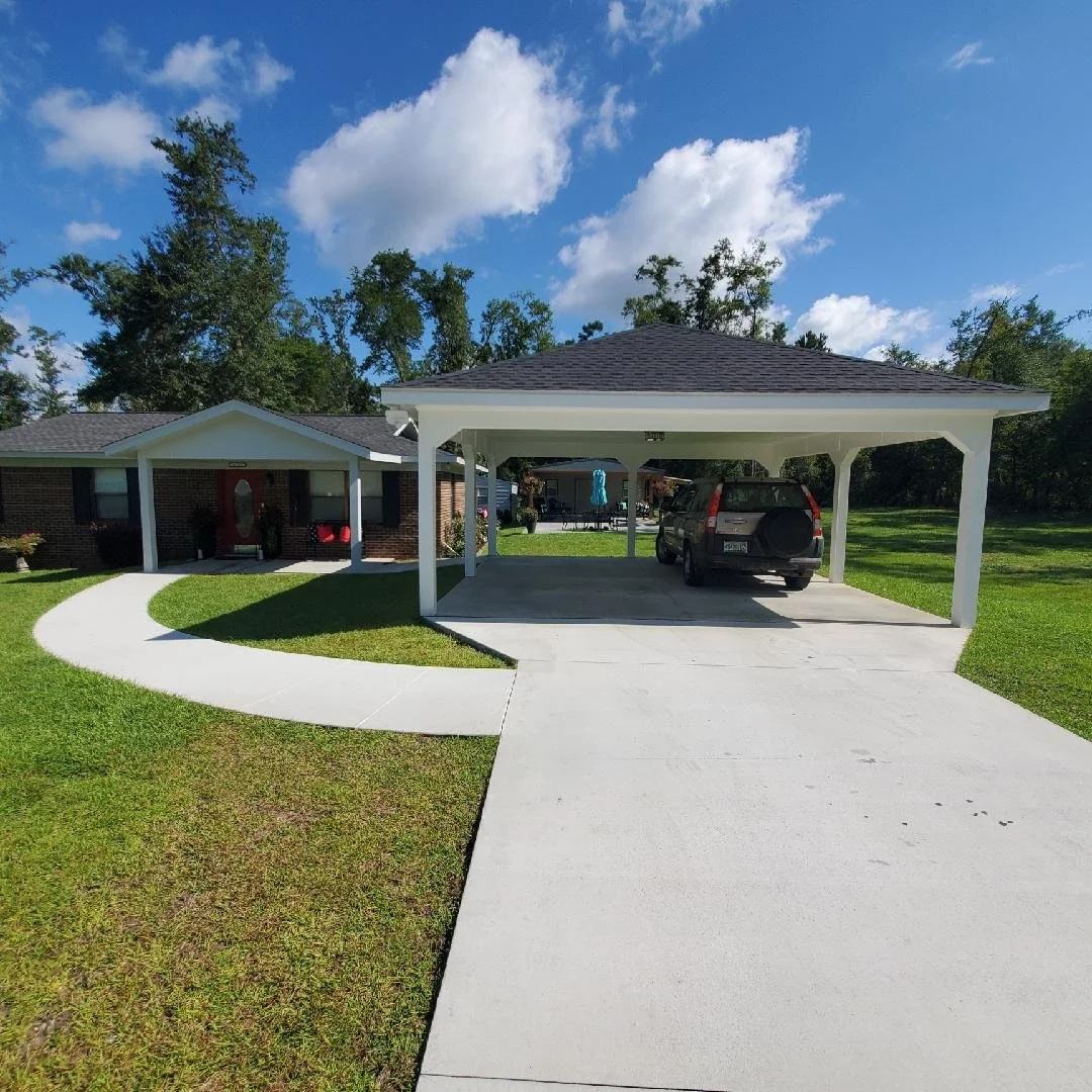 Completed residential exterior featuring a concrete driveway and walkway with carport constructed by Tindall Construction.
