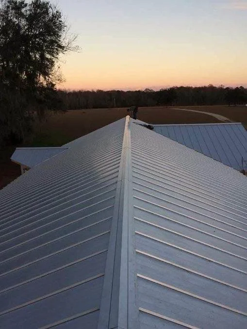 Aerial view of completed metal roof installation with ridge line detail, showcasing craftsmanship by Tindall Construction.